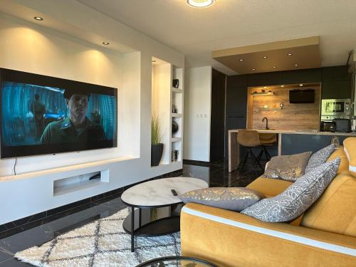 un salon avec un canapé et une télévision sur un mur dans l'établissement Charme et Confort à Borderouge, à Toulouse