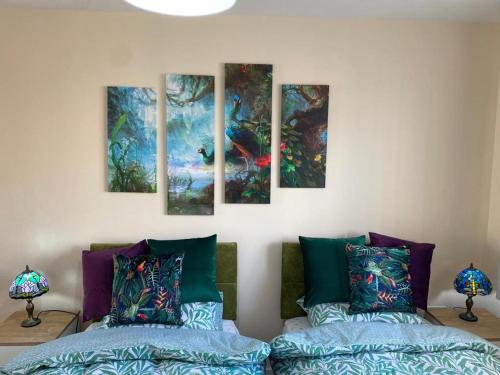 a room with two beds and paintings on the wall at Contemporary & Cosy Trumpington House, 5 mins to Bio Medical Campus, Addenbrooke's & Papworth hospitals in Cambridge