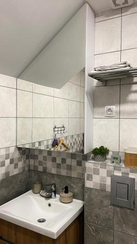 a bathroom with a white sink and a tile wall at Sanska 25 in Dušanovac (historical)