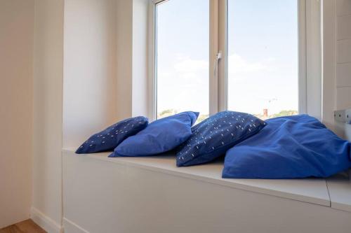 4 almohadas azules sentadas en un estante junto a una ventana en Fantastic sea views. One Bedroom flat near the sea, en Selsey