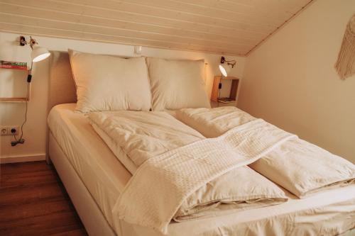uma cama com lençóis brancos e almofadas num quarto em ViLLA WASSERSTADT em Nordhorn