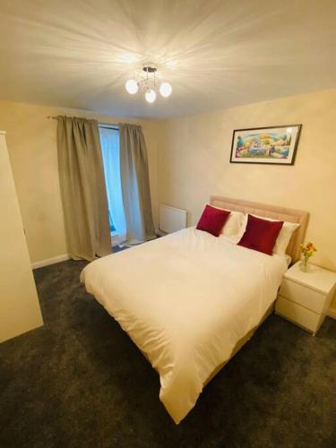 a bedroom with a large white bed with red pillows at Beautiful and Modern 2 bedroom flat in Colindale in Colindale