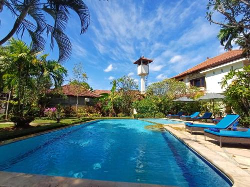 una piscina en un complejo con sillas y una torre de agua en Balinda Rooms & Villa, en Lovina