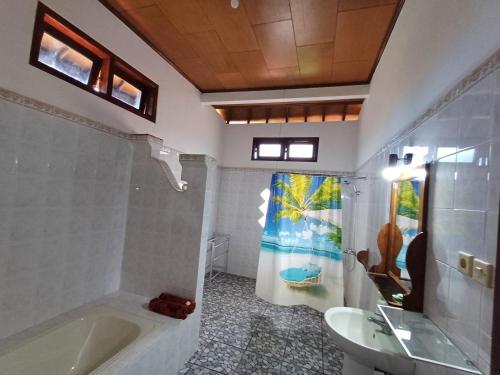 a bathroom with a tub and a sink at Balinda Rooms & Villa in Lovina