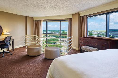 ヒューストンにあるシェラトン ノース ヒューストン アット ジョージ ブッシュ インターコンチネンタルのベッド、デスク、窓が備わるホテルルームです。