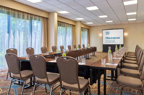 a conference room with long tables and chairs and a screen at Sheraton North Houston at George Bush Intercontinental in Houston