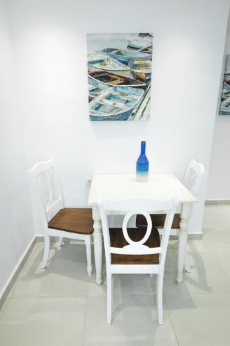 a white table with two chairs and a bottle on it at Theoxenia Kasos Luxury Apartments in Panayía
