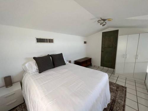 a white bedroom with a large white bed with black pillows at Upscale 2bdrm Condo In La Jolla in San José del Cabo