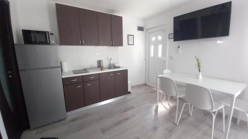 a kitchen with a white table and white chairs at Apartmani HERMES Jadrija in Šibenik