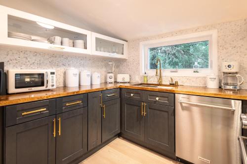 a kitchen with black cabinets and a sink and a microwave at THE SHORELINE CABIN in Kodiak