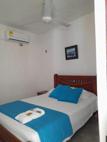 a bedroom with a bed with blue and white sheets at Hotel Isla Capri in Mompós