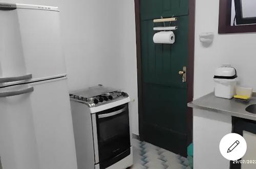 uma cozinha com um fogão e uma porta verde em Casa Cantinho de Buzios em Búzios