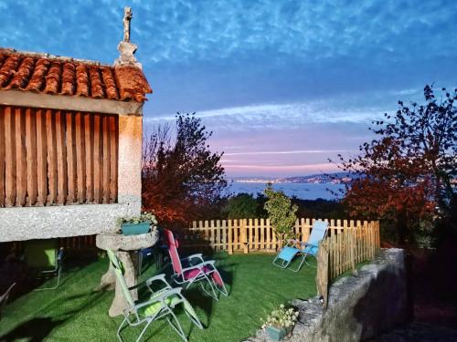 a yard with chairs and a fence with the sunset at El Mirador de playa LAPAMAN - BUEU in Marín