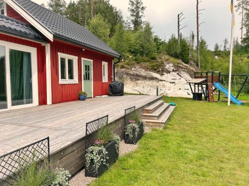a red house with a deck and a playground at The Buar Cabin in Strömstad