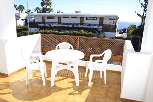 una mesa blanca y sillas en un balcón con tren en Apartamentos Tivoli, en Playa del Inglés