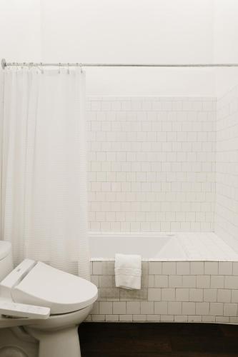 a white bathroom with a toilet and a bath tub at The Parador in Santa Fe