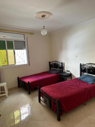 2 camas en una habitación con sábanas rojas en Rafi Apartments al Hoceima, en Alhucemas