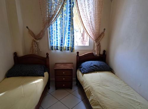 2 camas en una habitación pequeña con ventana en Apartment familiale oued laou, en Oued Laou
