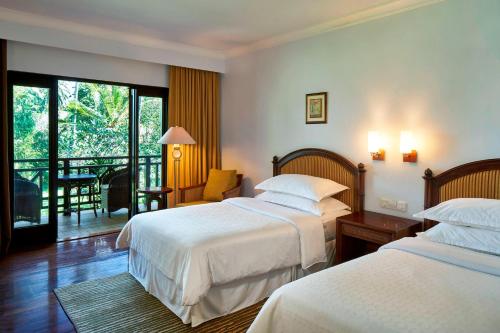 a hotel room with two beds and a balcony at Sheraton Senggigi Beach Resort in Senggigi