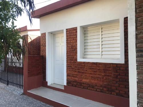a brick building with a white door and a window at comoencasa2 in Mercedes
