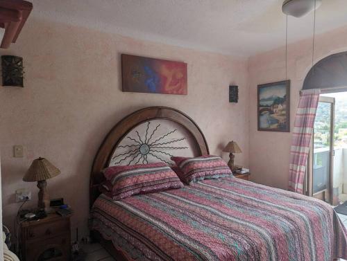a bedroom with a large bed with a wooden headboard at Vista Bahia Zihua in Zihuatanejo