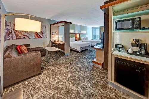 ムーアにあるSpringHill Suites by Marriott Oklahoma City Mooreのベッドとリビングルームが備わるホテルルームです。