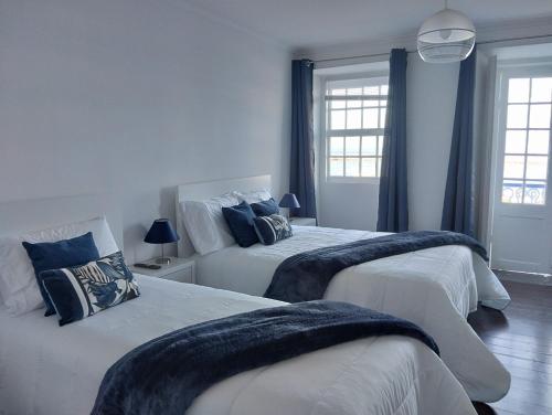 Duas camas num quarto com paredes e janelas azuis em SEASTAR nº36 em Horta