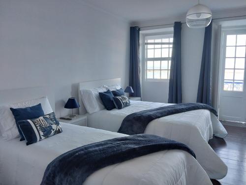 two beds in a bedroom with blue walls and windows at SEASTAR nº36 in Horta