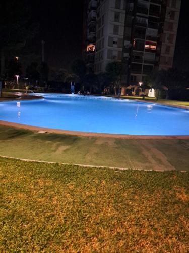 uma grande piscina azul numa cidade à noite em Playa de poblá farnals em Las Canteras