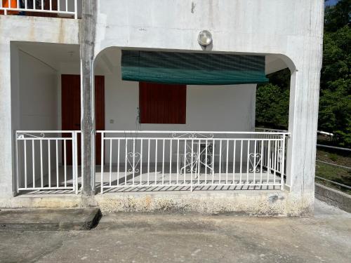 a white building with a balcony with a green awning at Le domaine de Luluc in Vieux-Habitants