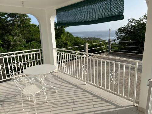 a balcony with a table and chairs and a view of the ocean at Le domaine de Luluc in Vieux-Habitants