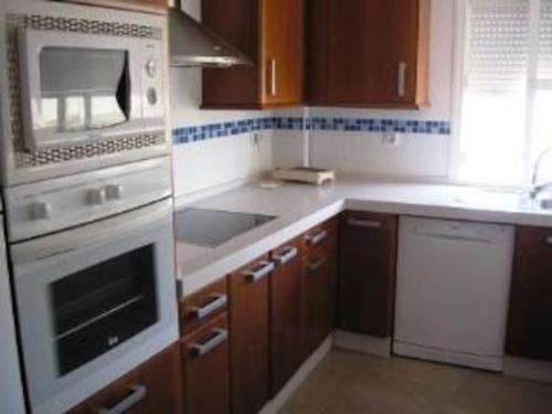 uma cozinha com armários de madeira e um forno de fogão branco em Apartamento en el centro 3 plazas con Aire Acondicionado Estancia minima 3 noches em El Puerto de Santa María