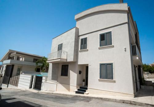 a white building with black shutters on it at Scirocco Holiday House DIAMANTE in Rosolini