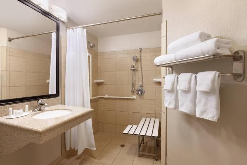 a bathroom with a sink and a shower with towels at Springhill Suites by Marriott West Palm Beach I-95 in West Palm Beach