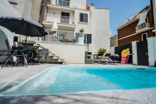 a swimming pool with an umbrella next to a building at Scirocco Holiday House LIMONE in Rosolini
