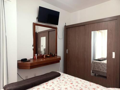 1 dormitorio con 1 cama con espejo y TV en Ap perto da praia, garagem privativa e wifi, en Florianópolis