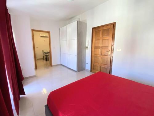 1 dormitorio con cama roja y puerta de madera en Attico sul Mare, en Vibo Valentia Marina