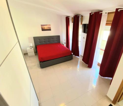 1 dormitorio con cama roja y cortinas rojas en Attico sul Mare, en Vibo Valentia Marina