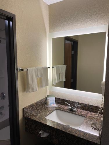 baño con lavabo y espejo grande en AmericInn by Wyndham Chippewa Falls, en Chippewa Falls