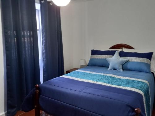 a bedroom with a blue bed with blue curtains at SEASTAR nº38 in Horta