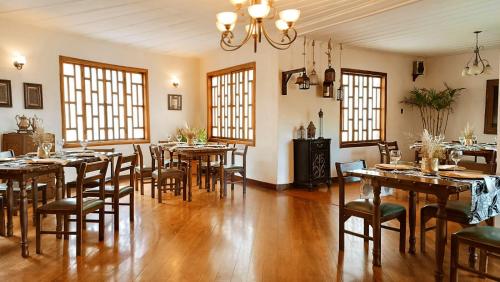 uma sala de jantar com mesas, cadeiras e janelas em QUINTA LOREN HOSTERIA em Ambato
