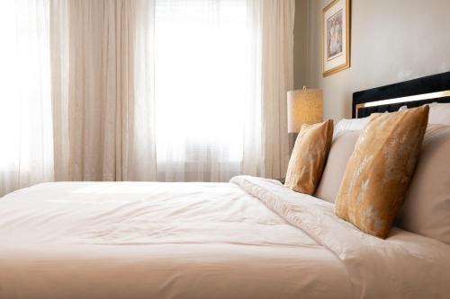 a bedroom with a large white bed with a window at Luxury Federal Hill Home with Rooftop & 4 Parking Spots in Baltimore