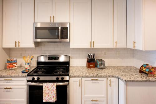 a kitchen with white cabinets and a stove and a microwave at Luxury Federal Hill Home with Rooftop & 4 Parking Spots in Baltimore