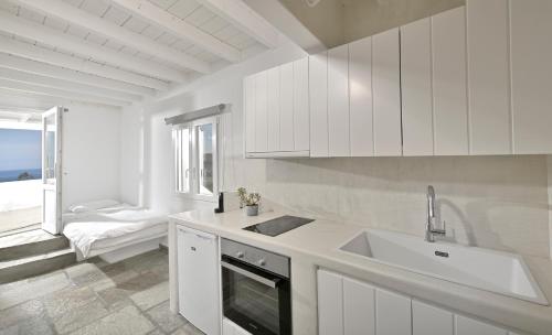 a kitchen with white cabinets and a sink and a window at VLIA MAR Myconian Residences in Kalafatis