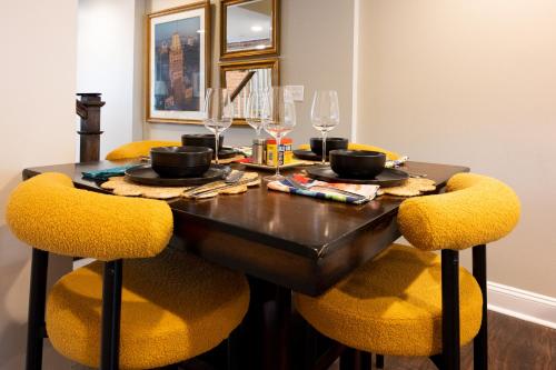 a dining room table with yellow chairs and a table with glasses at Luxury Federal Hill Home with Rooftop & 4 Parking Spots in Baltimore