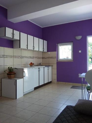 cocina con paredes moradas y armarios blancos en Apartment Marko, en Šibenik