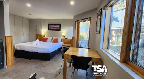 Un dormitorio con una cama, un escritorio y una mesa. en Powder 3A, en Thredbo