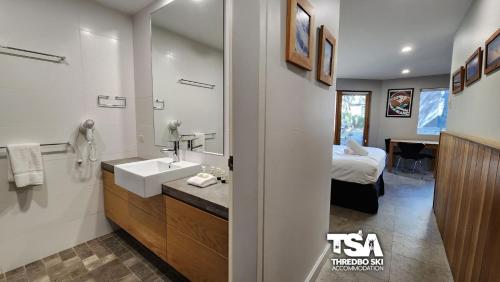 a bathroom with a sink and a bedroom with a bed at Powder 3A in Thredbo