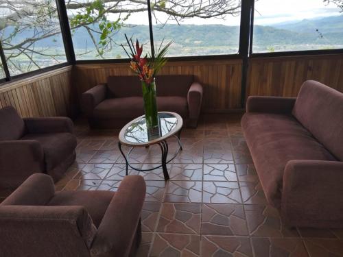 a living room with couches and a table with a vase of flowers at Hotel Green Mountain turrialba in Turrialba