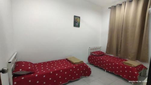 two beds in a room with red sheets with polka dots at Marissa Homestay 2 in Cukai